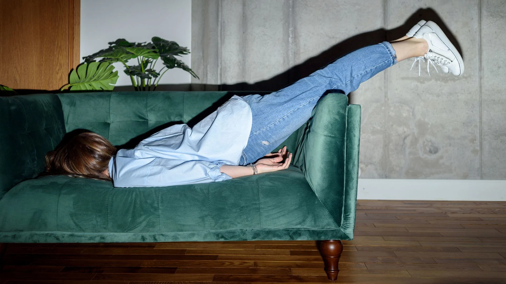 Adult lays face down on a sofa.